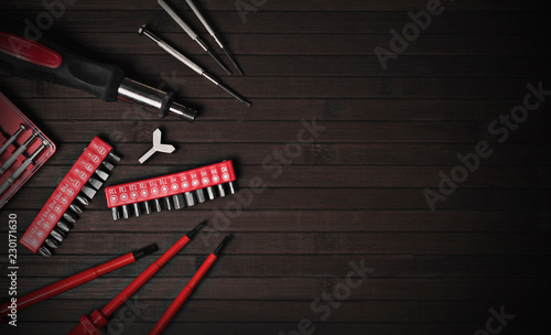 set of screwdrivers and replaceable bits on a black wooden background