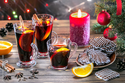 Christmas mulled red wine with spices and fruits on a wooden table. Traditional hot drink at New Year and Christmas time.