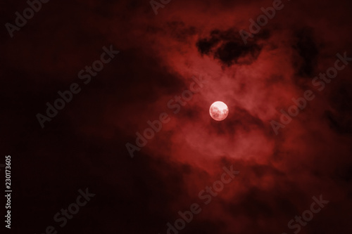 Full moon covered red clouds in the night sky