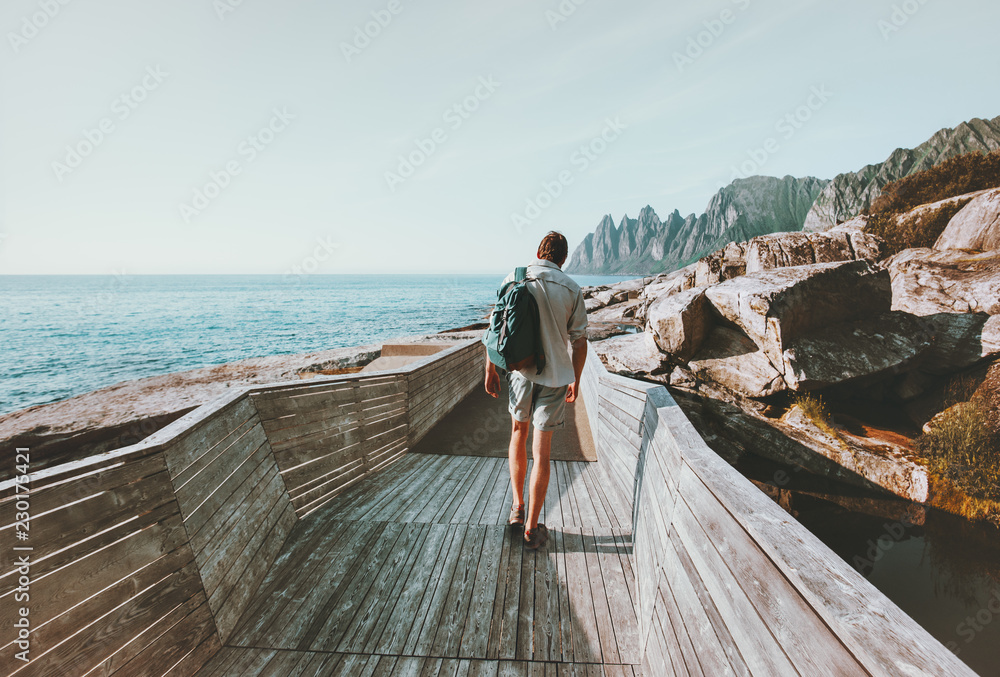 Man traveler walking on wooden bridge Traveling in Norway lifestyle adventure  vacations outdoor