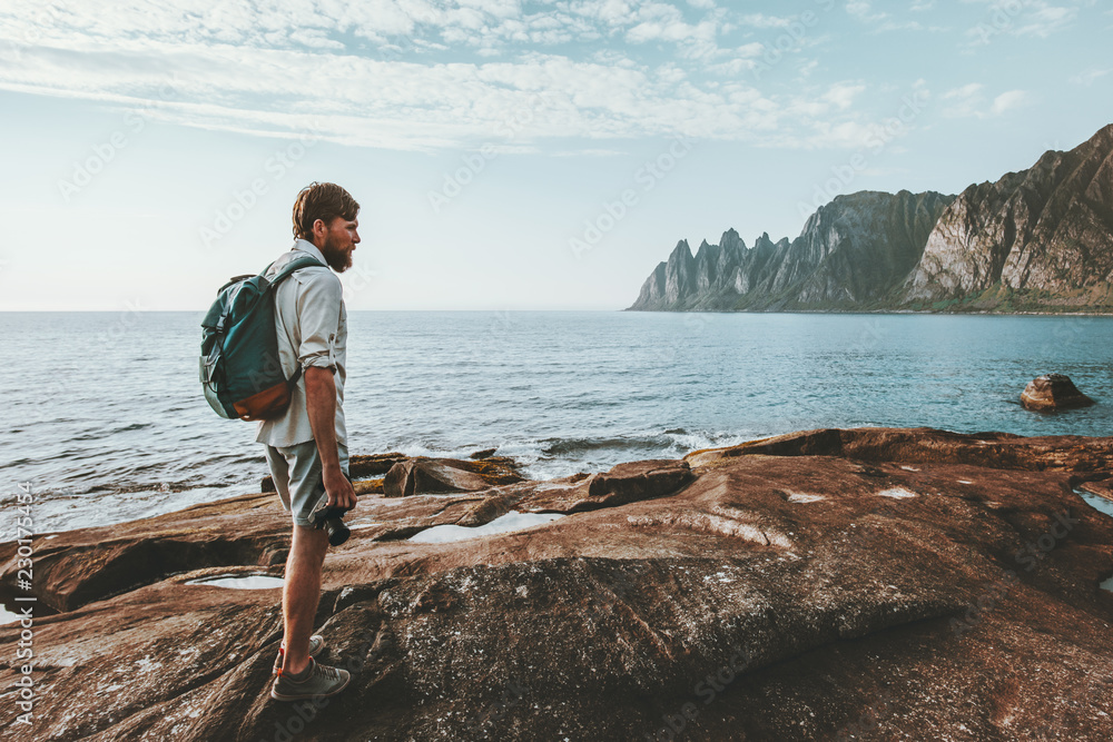 Man backpacker walking alone on beach traveling in Norway lifestyle summer vacations outdoor Okshornan peaks view Man backpacker walking alone on beach traveling in Norway lifestyle summer vacations outdoor Okshornan peaks view