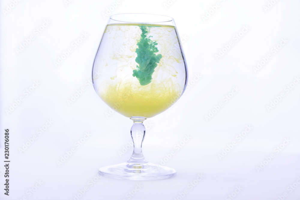 Colorful paint in water in a crystal glass on a white background Colorful paint in water in a crystal glass on a white background