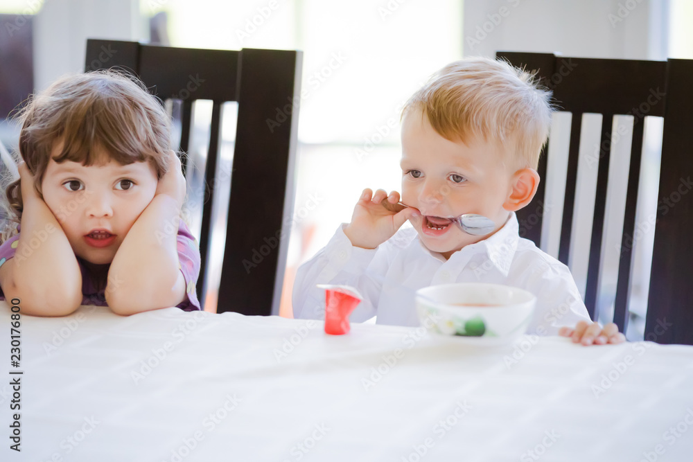 Cute toddler boy and girl eating soup together at home Cute toddler boy and girl eating soup together at home