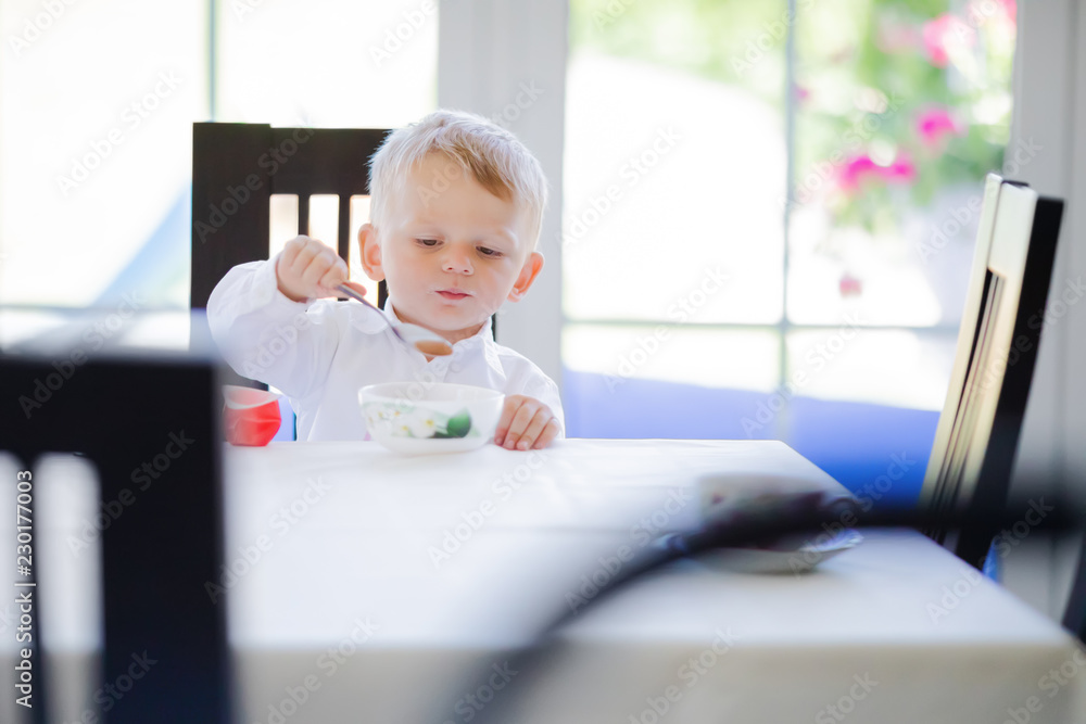 Cute toddler boy eating soup with spoon at home Cute toddler boy eating soup with spoon at home