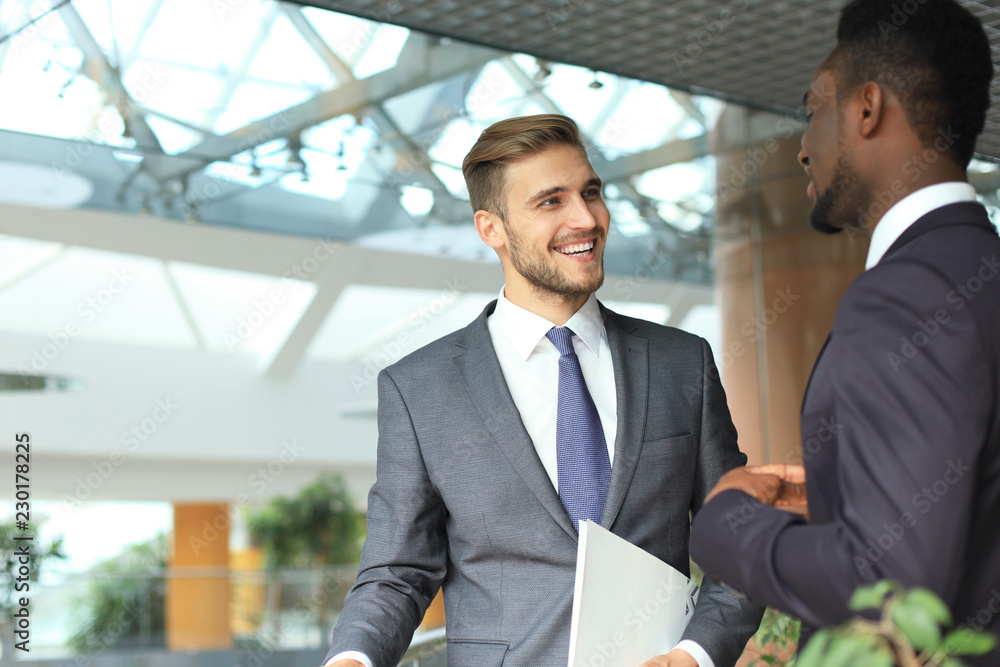 Fototapeta premium Two multinational young businessmen discussing business at meeting in office.