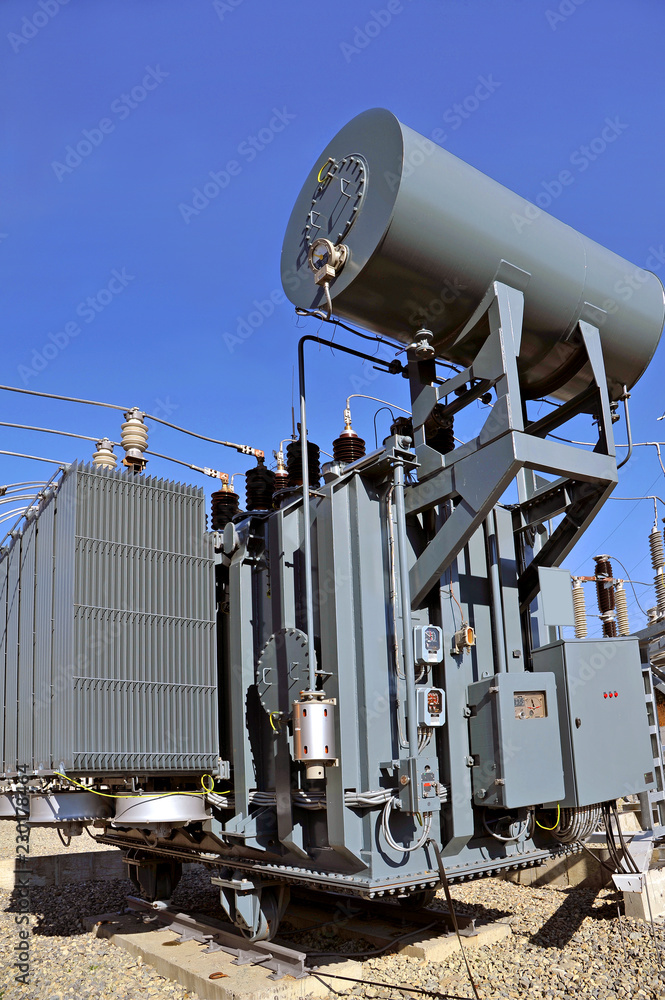 High voltage oil-filled power transformer on electrical substation.Part of  high-voltage substation with switches and dis connectors on blue sky  background Stock-Foto