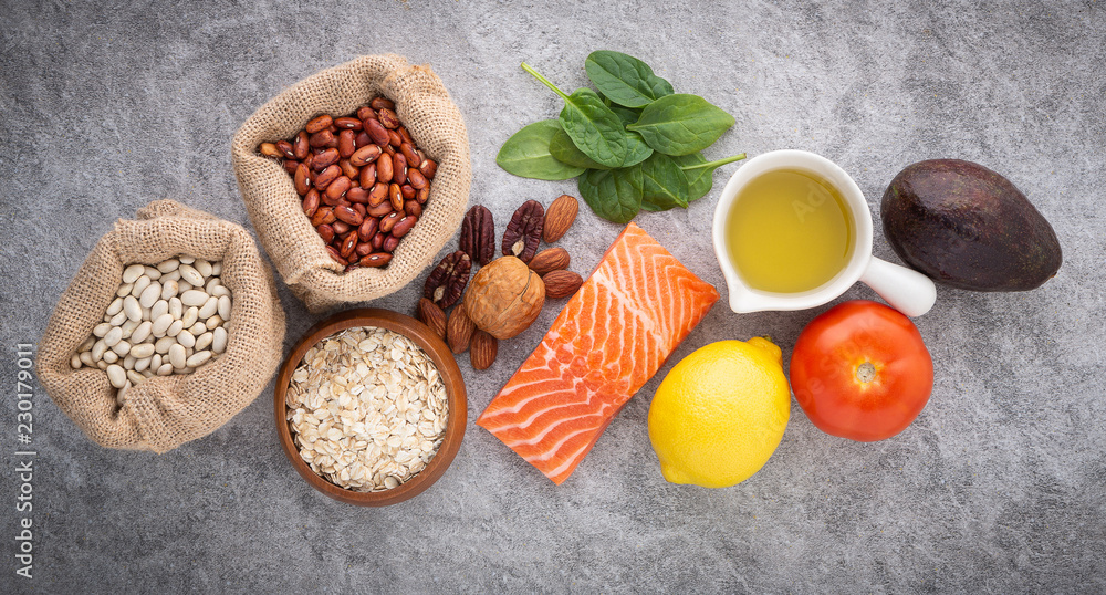 selection of healthy food. Salmon fish, nuts, fruits and vegetables on stone background from top view.