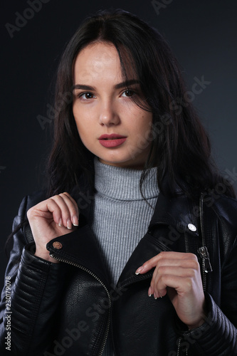 Portrait of girl in black leather jacket on gray background