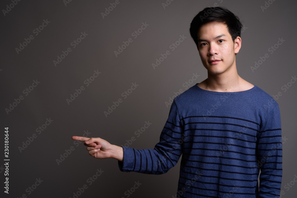 Asian man showing copy space with pointing finger Asian man showing copy space with pointing finger