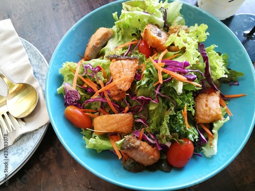 Fried salmon salad in blue dist on table in Thai restaurant photo