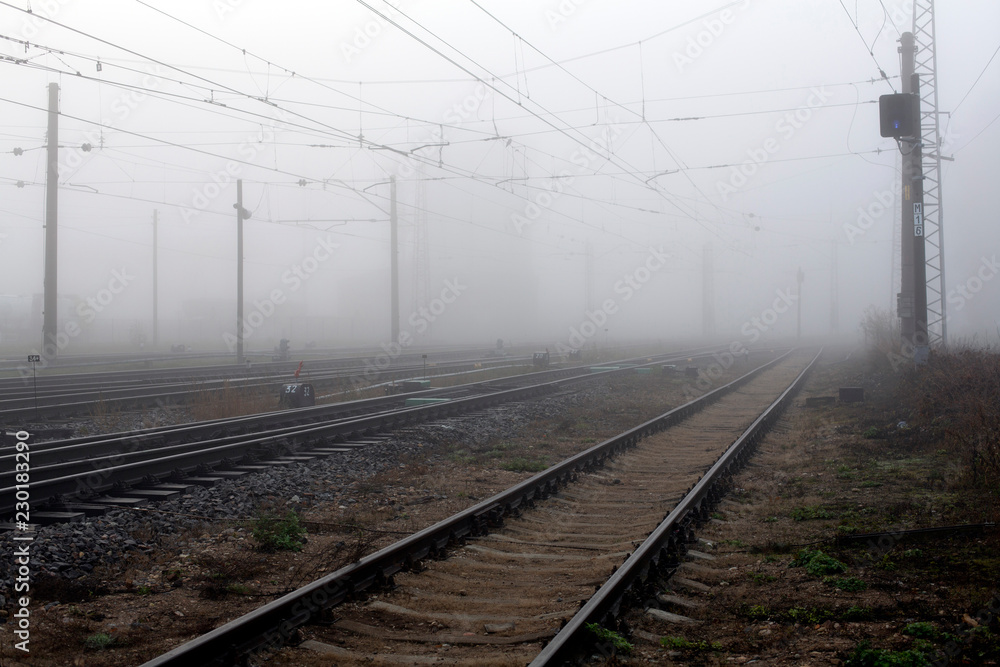 Crossing railways disappearing  fading away in the mist in autumn morning