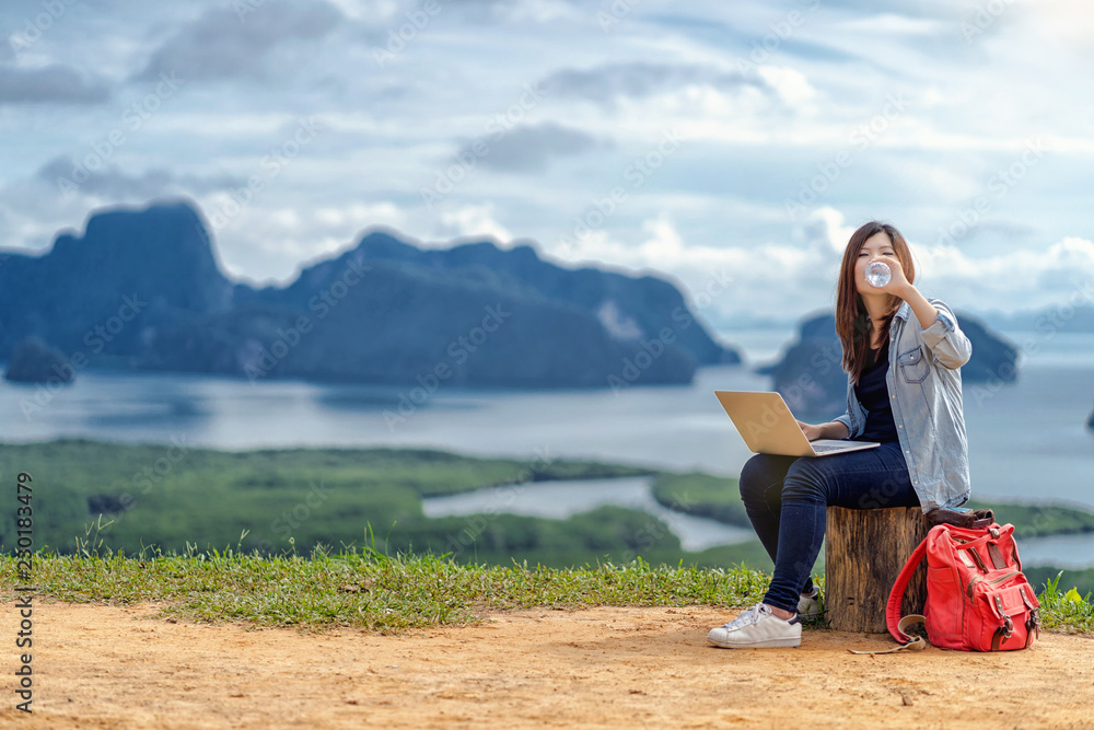 Asian woman freelancer working with technology laptop and drinking the water at Fantastic Landscape of samed nang chee view point, Freelance working and travel anywhere concept