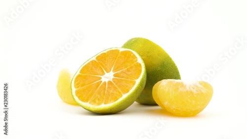 Two halves of a green tangerine fruits with water drops. Green mandarin slices rotating. Isolated on the white background. Close-up. Macro. photo