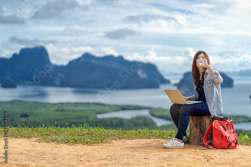 Obraz na płótnie Asian woman freelancer working with technology laptop and drinking the water at Fantastic Landscape of samed nang chee view point, Freelance working and travel anywhere concept w salonie