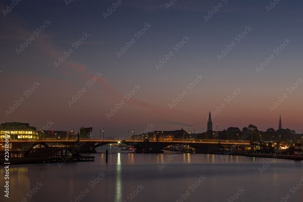 Waterside buildings in Copenhangen during a colorful sunrise reflecting in the water channel