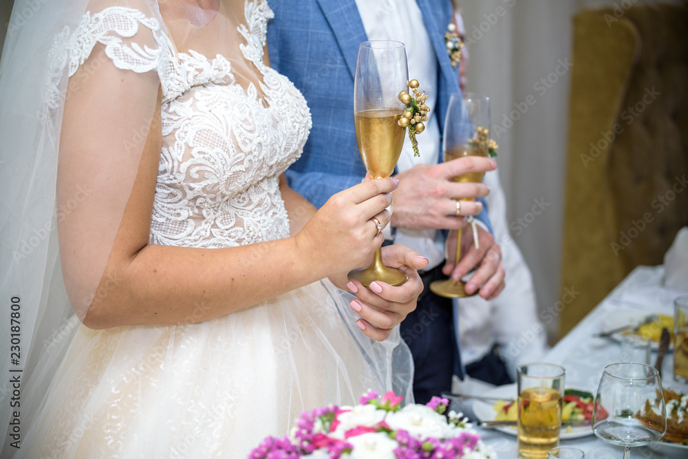 Bride and groom at the wedding table. holding a glass of champagne Bride and groom at the wedding table. holding a glass of champagne