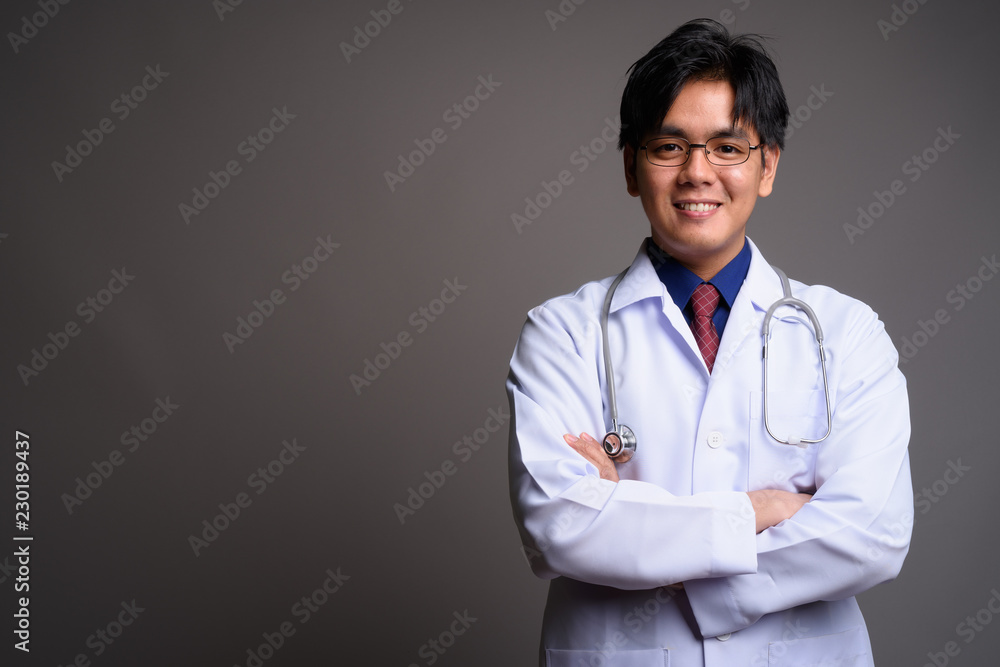 Happy young Asian man doctor smiling with arms crossed Happy young Asian man doctor smiling with arms crossed