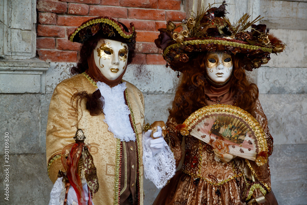 Colorful carnival gold-brown mask and costume at the traditional festival in Venice, Italy