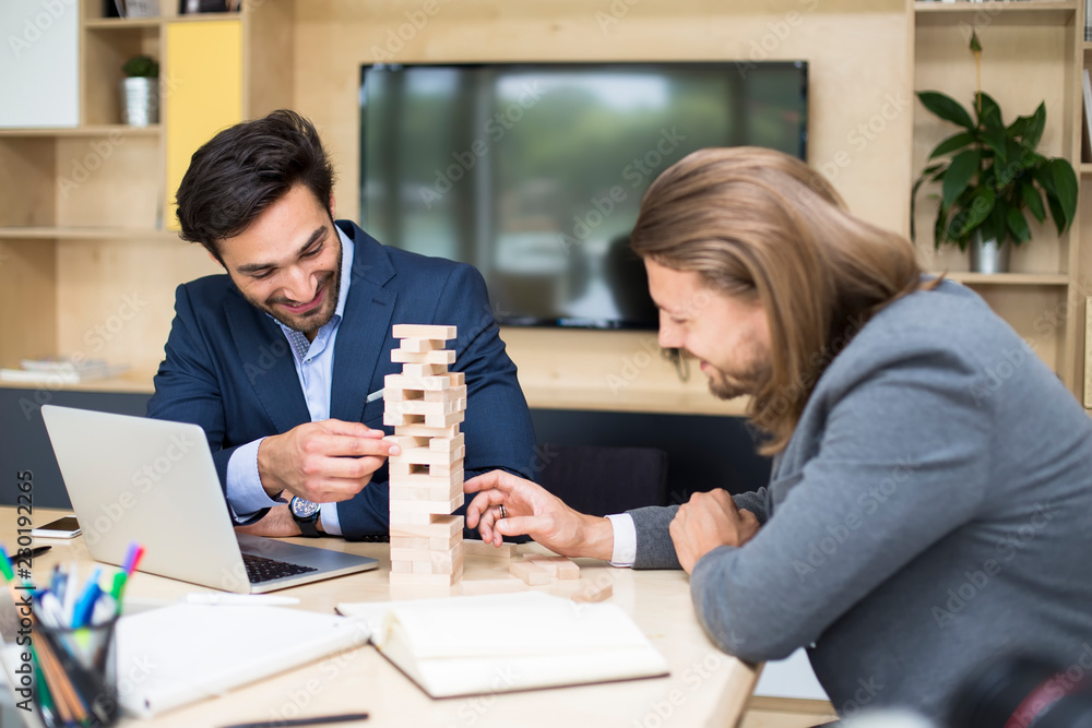 Fototapeta premium Team of young business people build a wooden construction in the office