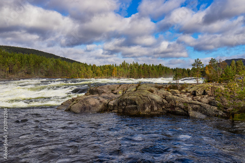 A wild river floating through rocks an trees. In the wonderfull landscape of Norway there are no people.