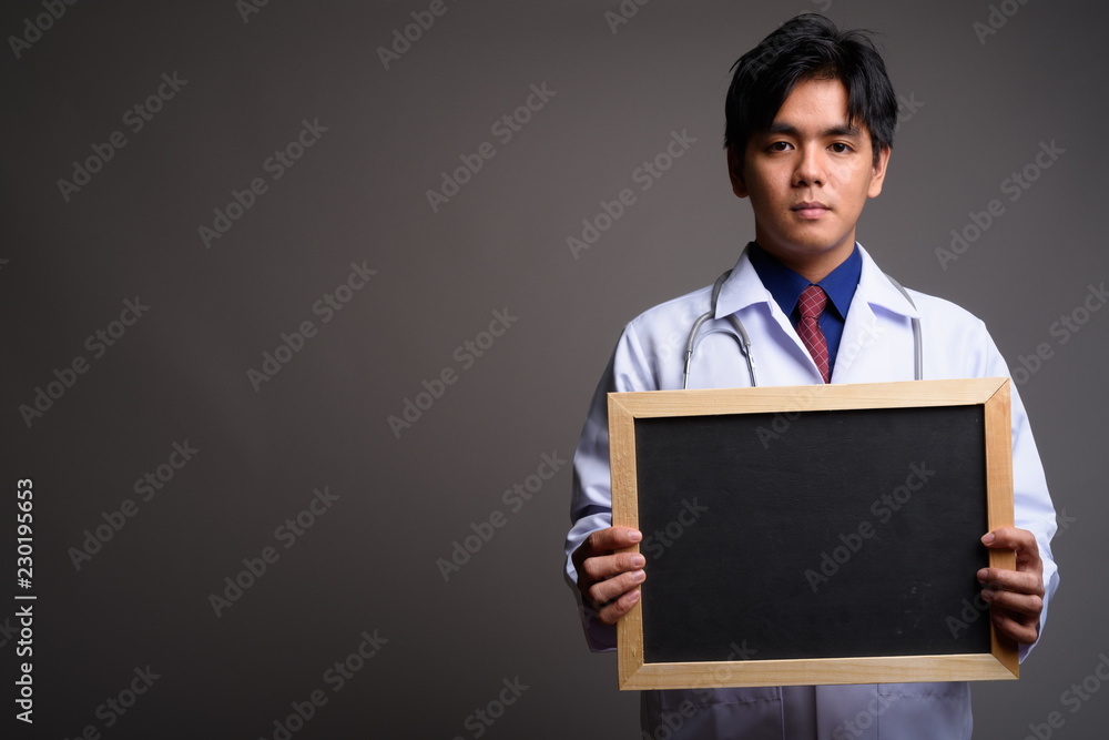Asian man doctor holding empty blackboard with copyspace Asian man doctor holding empty blackboard with copyspace