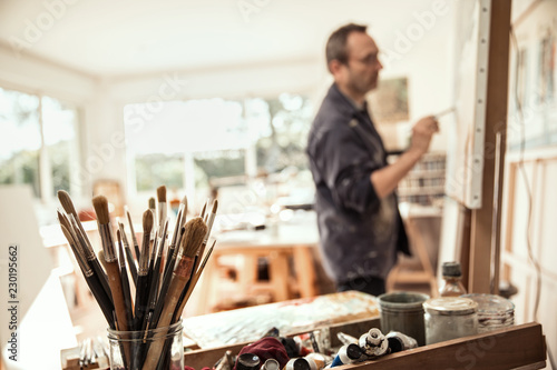 A painter in his studio working on a canvas at sunrise