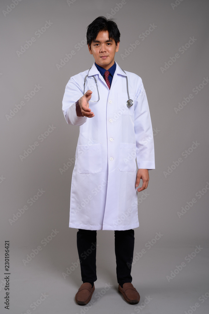 Full length portrait of young Asian man doctor giving handshake Full length portrait of young Asian man doctor giving handshake