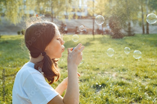 Teen girl having fun in the park - blowing soap bubbles  golden hour