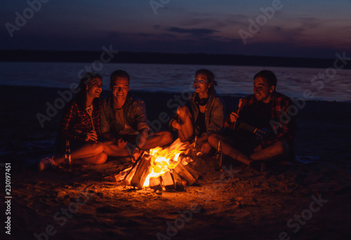 Camp on the beach. Group of young friends having picnic with bonfire. They have fun