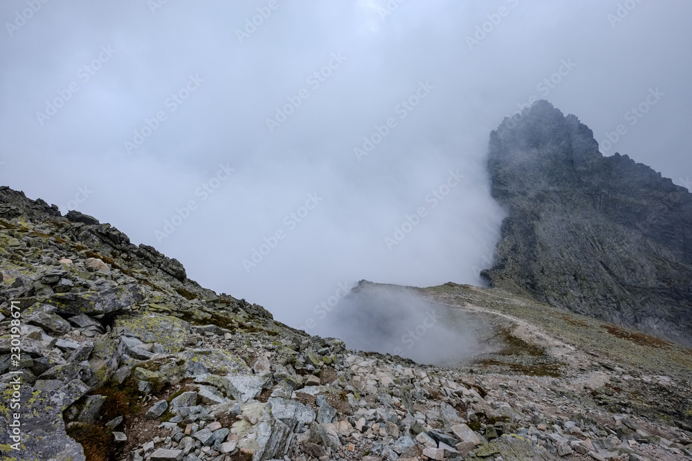 peak of Rysy mountain covered in mist. autumn ascent on hiking trails