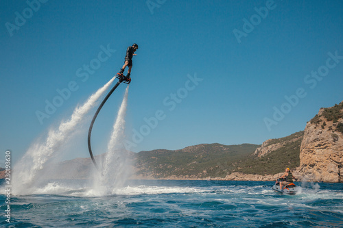 Flyboarding and seariding on the Sea near the mountain island. Water summer extreme sports. photo