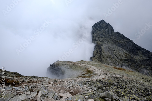 peak of Rysy mountain covered in mist. autumn ascent on hiking trails