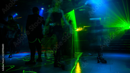 People dancing under green strobe lights in the dark. Entertainment  leisure and nightlife concept. Adult lifestyle.