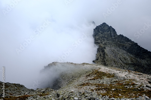 peak of Rysy mountain covered in mist. autumn ascent on hiking trails