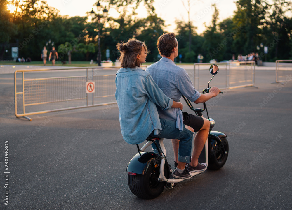 Lovely young couple driving electric bike during summer. Modern city dating and transportation Lovely young couple driving electric bike during summer. Modern city dating and transportation