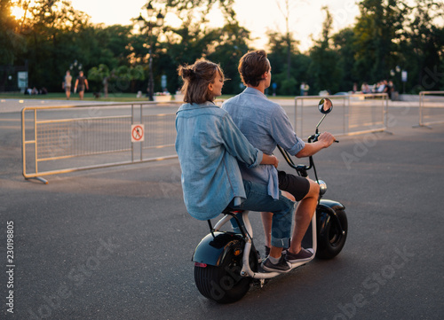 Lovely young couple driving electric bike during summer. Modern city dating and transportation