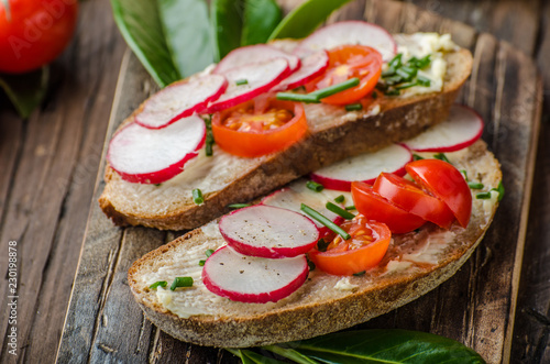 Homemade bread with fresh creame, herbs and radishes