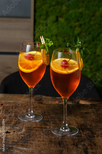 Two glasses of red cocktail with orange slice and cherry