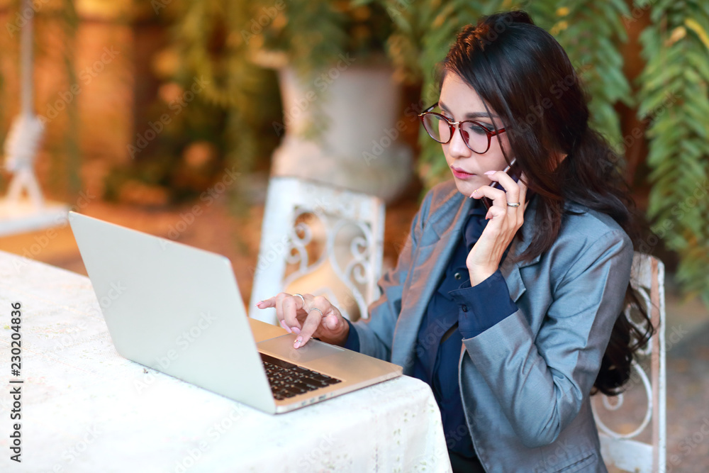 cute and charming businesswoman with glasses working on laptop computer and cell phone from restaurant or cafe cute and charming businesswoman with glasses working on laptop computer and cell phone from restaurant or cafe
