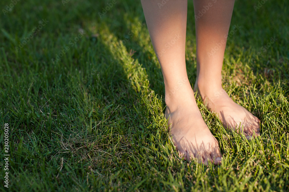 Close up on female feet standing barefoot on green grass.