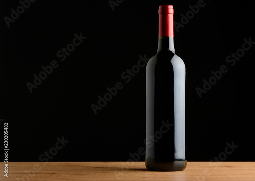 Botella de vino tinto en la mesa sobre fondo negro