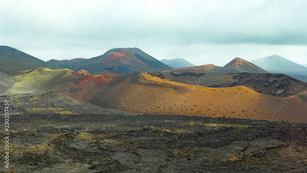 colrorful volcanic landscape with a big crater and lava field in the foreground