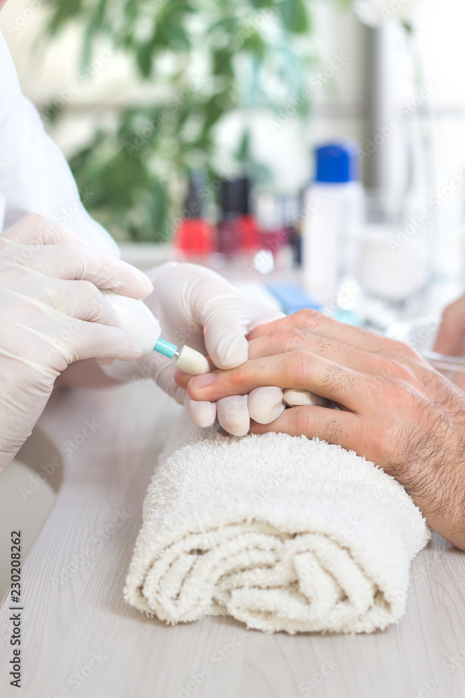 Obraz premium Męskie dłonie podczas zabiegu manicure w salonie kosmetycznym. 