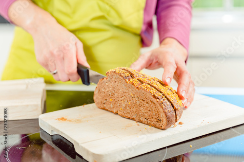 Close-up of woman cutting healthy bread for sandwich