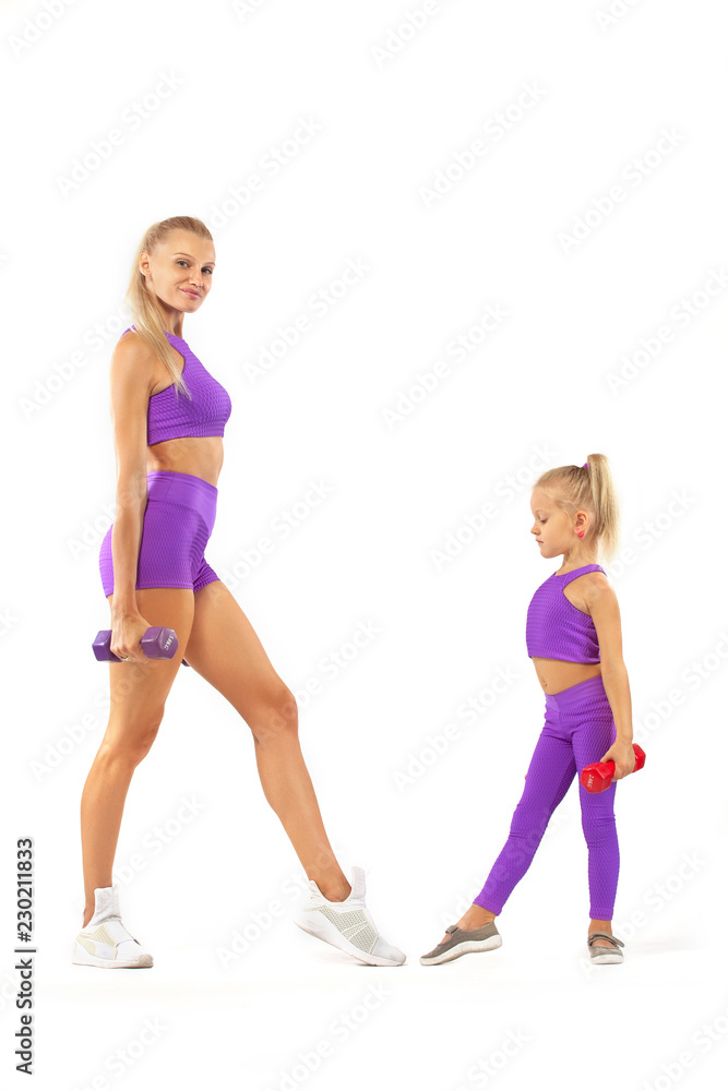 Mother trainer and kid girl doing fitness exercises with dumbbells on white background Mother trainer and kid girl doing fitness exercises with dumbbells on white background