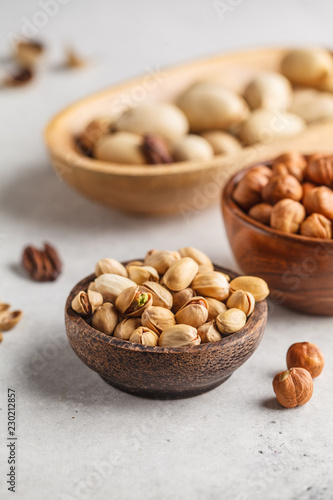 Pecans, hazelnuts and pistachios nuts in a wooden bowls on a white background.