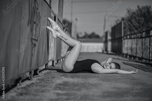 Monochrome portrait of beautiful ballerina wearing black tights and laying on the bridge