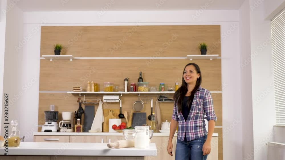 Portrait of gorgeous woman in the kitchen walking in front of the camera and smiling. Dolly slider 4K footage Portrait of gorgeous woman in the kitchen walking in front of the camera and smiling. Dolly slider 4K footage