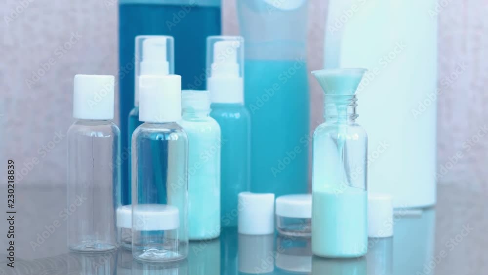 Pour blue shampoo in a small bottle of big through a funnel. Travel set of jars. Bottles close-up. Pour blue shampoo in a small bottle of big through a funnel. Travel set of jars. Bottles close-up.
