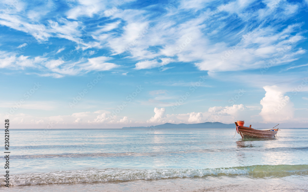 Obraz premium beautiful beach in morning sunrise and cloudy blue sky with fisherman boat